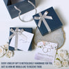 a blue gift box with a silver ribbon and a card